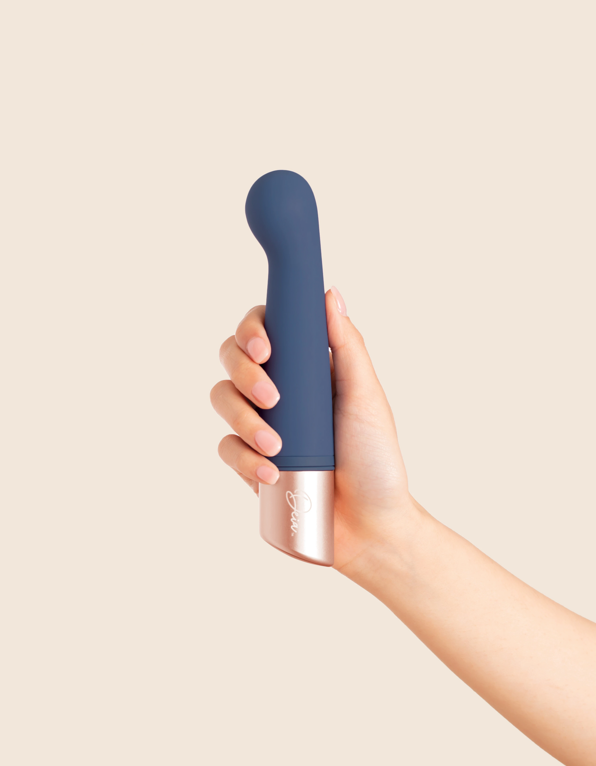 Hand holding a blue and silver device against a beige background