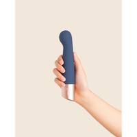 Hand holding a blue and silver device against a beige background