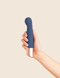 Hand holding a blue and silver device against a beige background