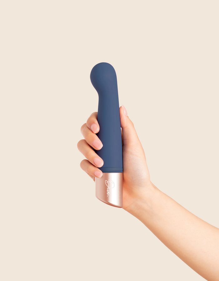 Hand holding a blue and silver device against a beige background