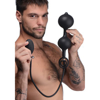 Man holding a black inflatable anal beads with cock ring device against a white background