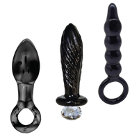Three black glass butt plugs of different sizes on a white background