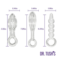 Three clear silicone or glass anal plugs shown side by side with dimension labels and purple measurement lines. The left item is 1.