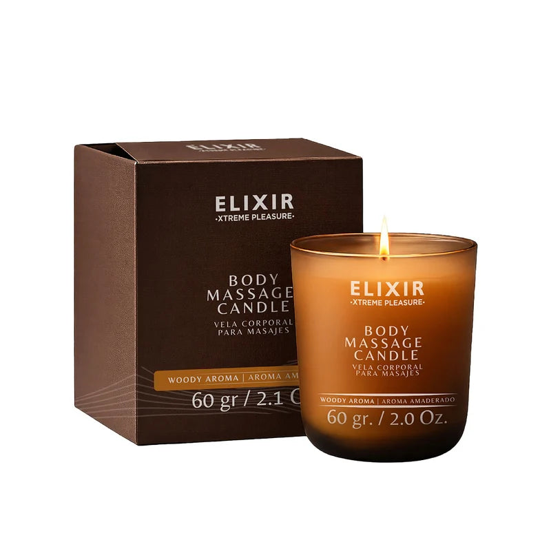 Elixir Body Massage Candle with warm woody aroma, 60 g, shown lit beside its brown product box