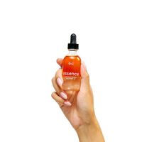 Hand holding a bottle of 'essence' oil with a dropper on a white background
