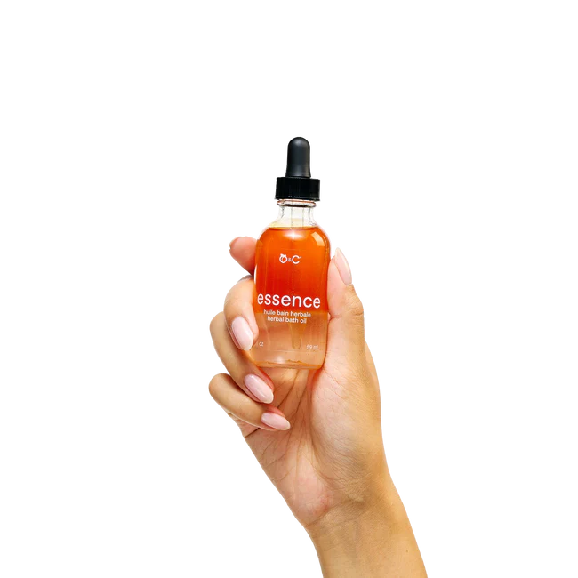 Hand holding a bottle of 'essence' oil with a dropper on a white background