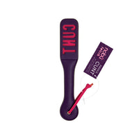 A purple leather paddle with 'CUNT' printed vertically in pink on the head, featuring a pink wrist strap and a matching pink product tag 