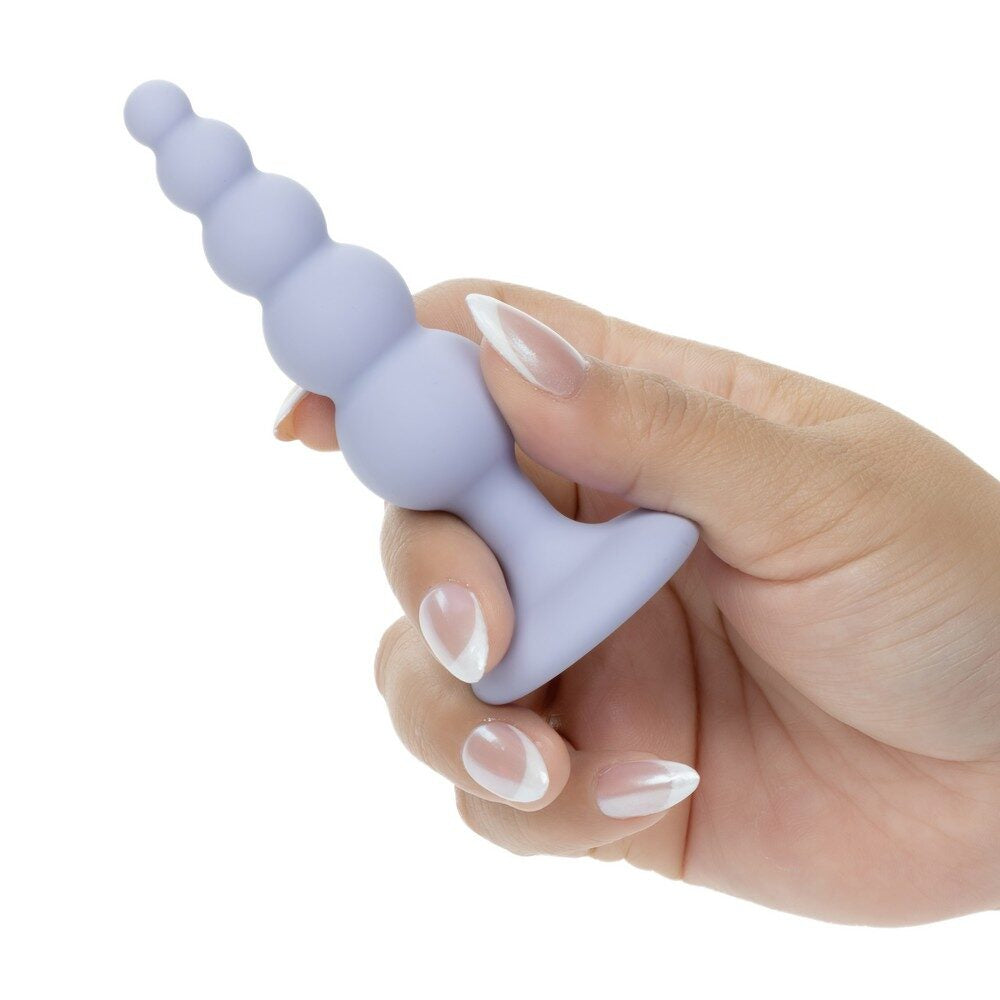 Hand holding a purple silicone anal probe on a white background