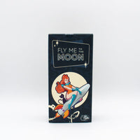 Product packaging with 'Fly Me to the Moon' text and a retro-style illustration of a woman on a moon surface.