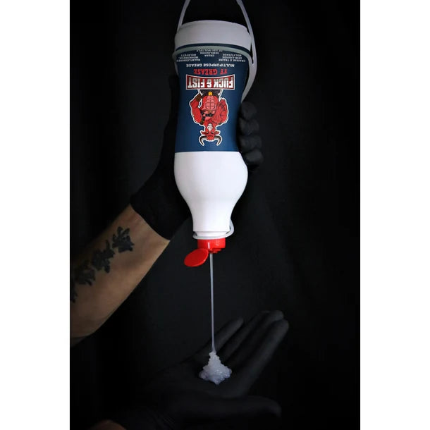 Hand holding a white and blue bottle with red cap, labeled 'fuck & fist', against a black background.