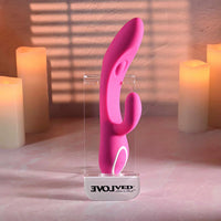 Pink silicone vibrator on a clear stand with candles in the background