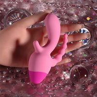 Pink silicone product held between fingers against a glittery background
