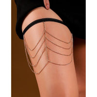 Gold chain leg accessory on a person's leg with a plain background
