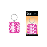 The image shows a metal keychain with the phrase 'GIRLS GIRLS GIRLS' in bold pink letters. The keychain is displayed both on its own and in packaging that includes a backing card and polybag.