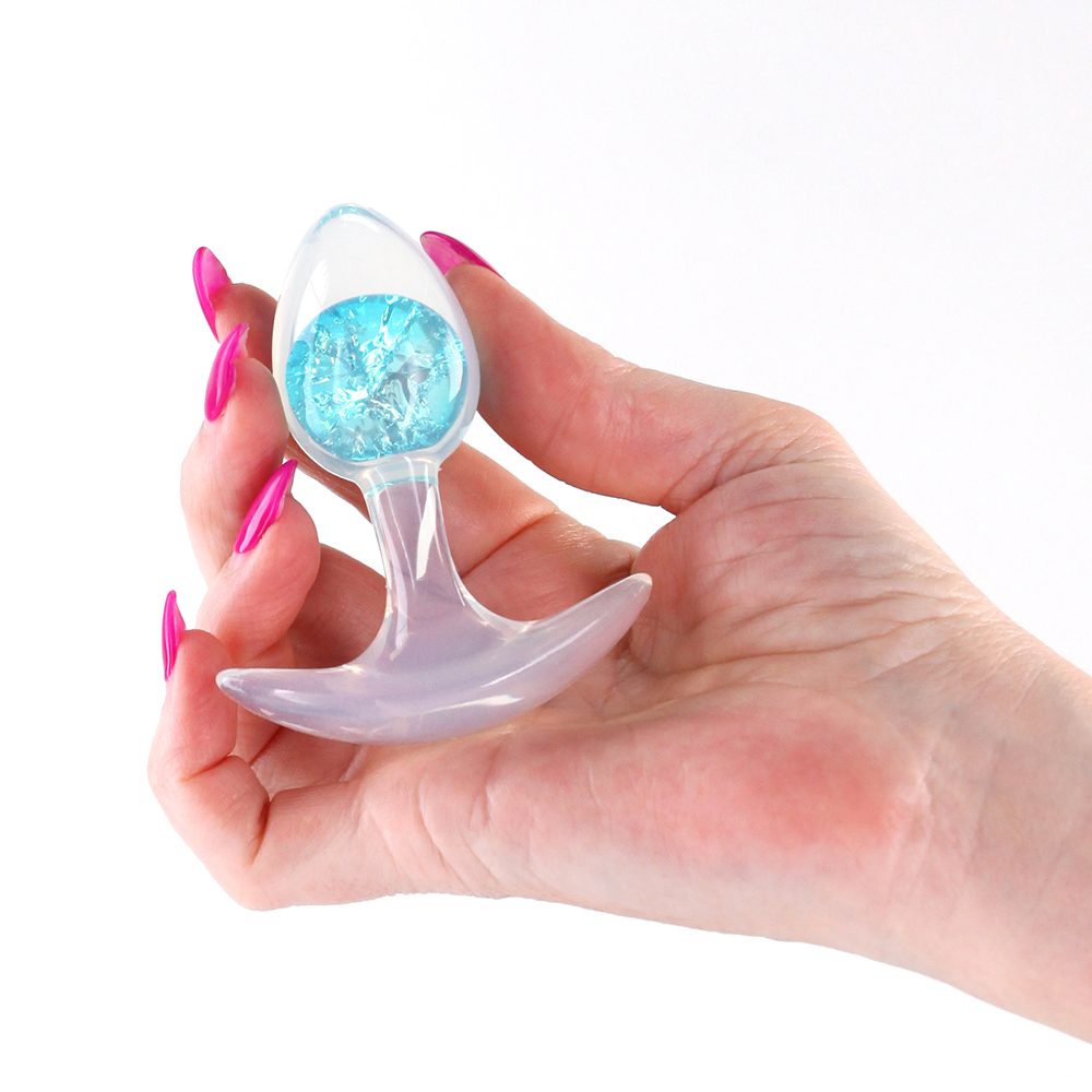 Hand holding a glams cosmic glass anal plug in blue on a white background