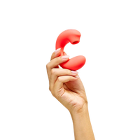 Hand holding a red silicone clitoral vibrator toy on a white background
