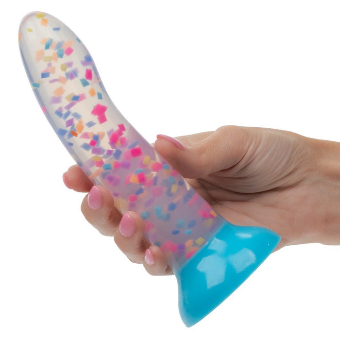 Hand holding a colorful, confetti filled dildo against a white background