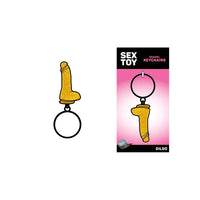 The image features the "Glitter Dildo" Metal Keychain by Wood Rocket, which is pink and has a sparkling, playful design. It is displayed both on its own and in packaging that includes a stylish 5" x 2.