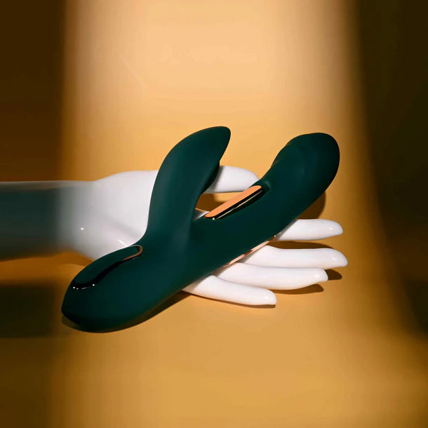 Dark green vibrator on a white mannequin hand against a warm brown background