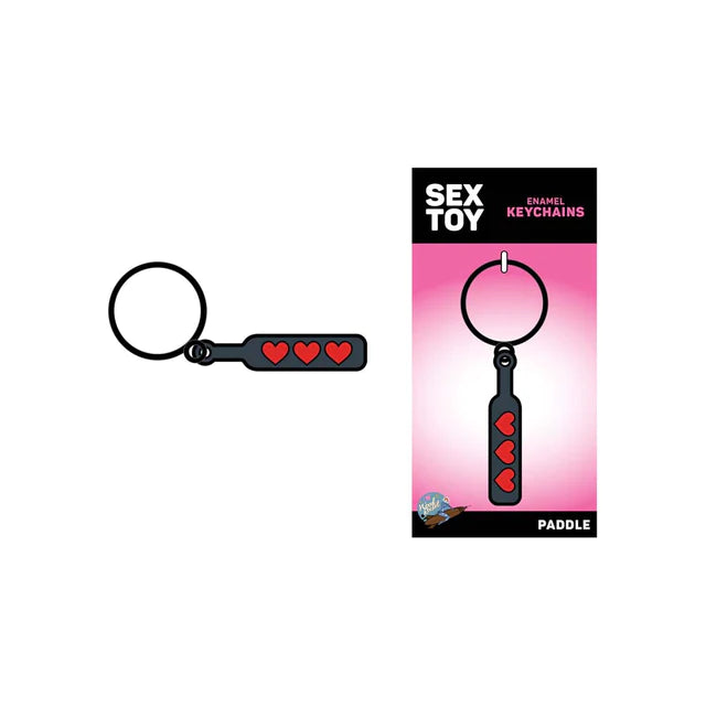 The image shows a black metal keychain with a playful heart paddle design, displayed alongside its packaging which indicates it is a product from the 'Sex Toy' category.