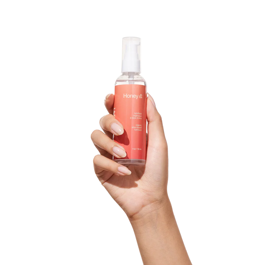 Hand holding a bottle of Honey silicone lube on a white background