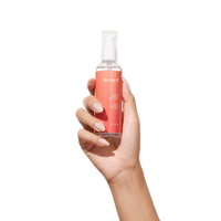 Hand holding a bottle of Honey lube on a white background