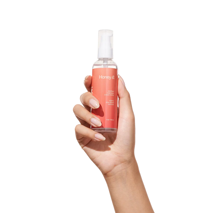 Hand holding a bottle of Honey lube on a white background