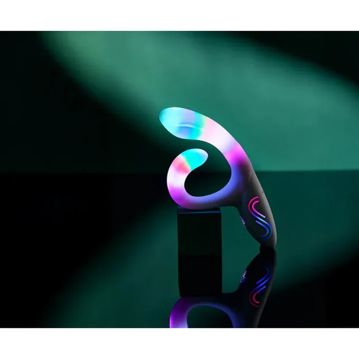 Colorful LED rabbit vibrator on a reflective surface with a dark background