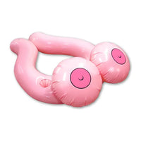 This image features the Inflatable Boobie Pool Floater, a playful and humorous pool accessory designed by Ozze Creations. The float, inflated to a size of 33 inches, is crafted in a soft pink color, depicting a pair of breasts with rosy cheeks and eyes, adding a whimsical touch.