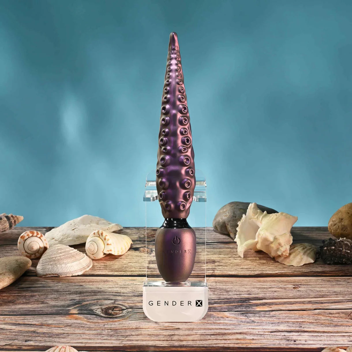 Purple GenderX vibrator with seashells on a wooden surface