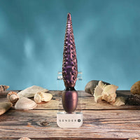 Purple GenderX vibrator with seashells on a wooden surface