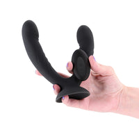 Black silicone double ended vibrator held in a hand against a white background