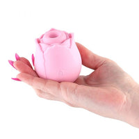 Pink rose-shaped vibrator held in a hand against a white background