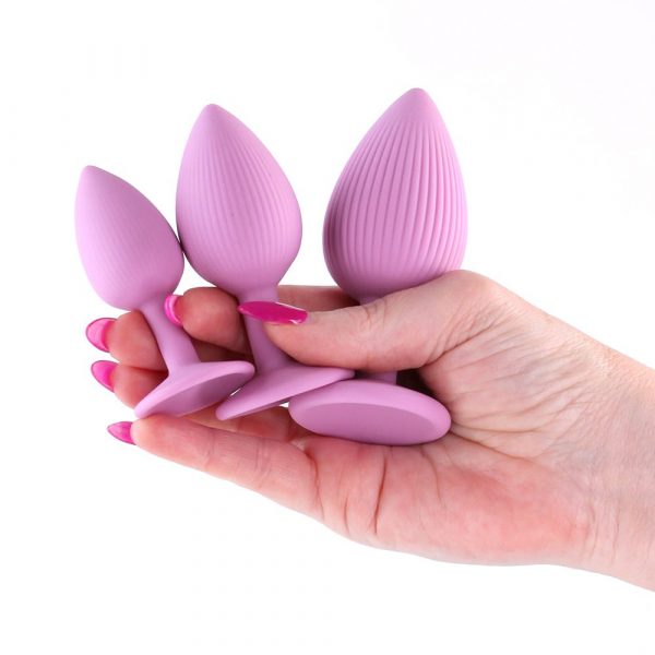 Set of pink silicone butt plugs held in a hand on a white background