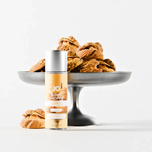 Bottle of JO Bake Shoppe orange creampuff lube with pastries on a white background