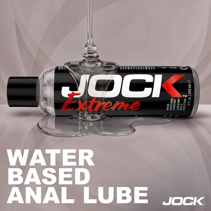 JOCK Extreme water-based anal lube bottle with a glass on a gray background