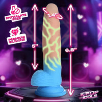 An adult novelty product shown on a glowing display base against a purple party background, with overlaid dimension arrows and text reading 5 inches, 1.4 inches, 6.