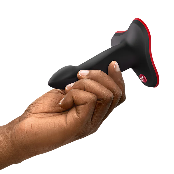 Hand holding a black and red limba flex s dildo device on a white background