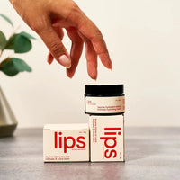 Hand reaching towards a 'lips' product on a neutral background
