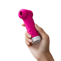 Pink handheld device held in a hand against a white background