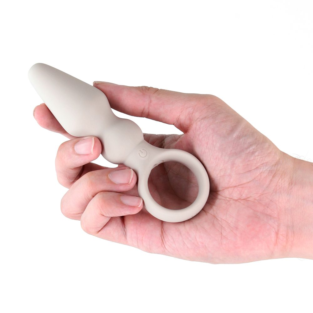 Hand holding a finger ring butt plug against a white background