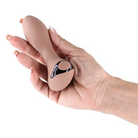 Hand holding a beige anal plug with a power button on a white background