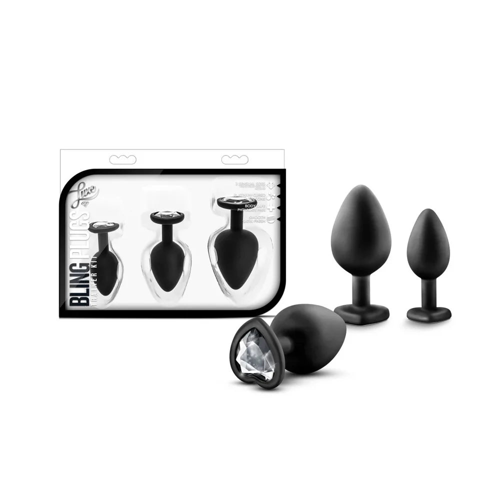 3 black anal plugs with clear heart gem bottoms beside box package