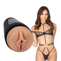 adult star stella barey wearing black teddy, standing beside realistic molded vagina masturbator