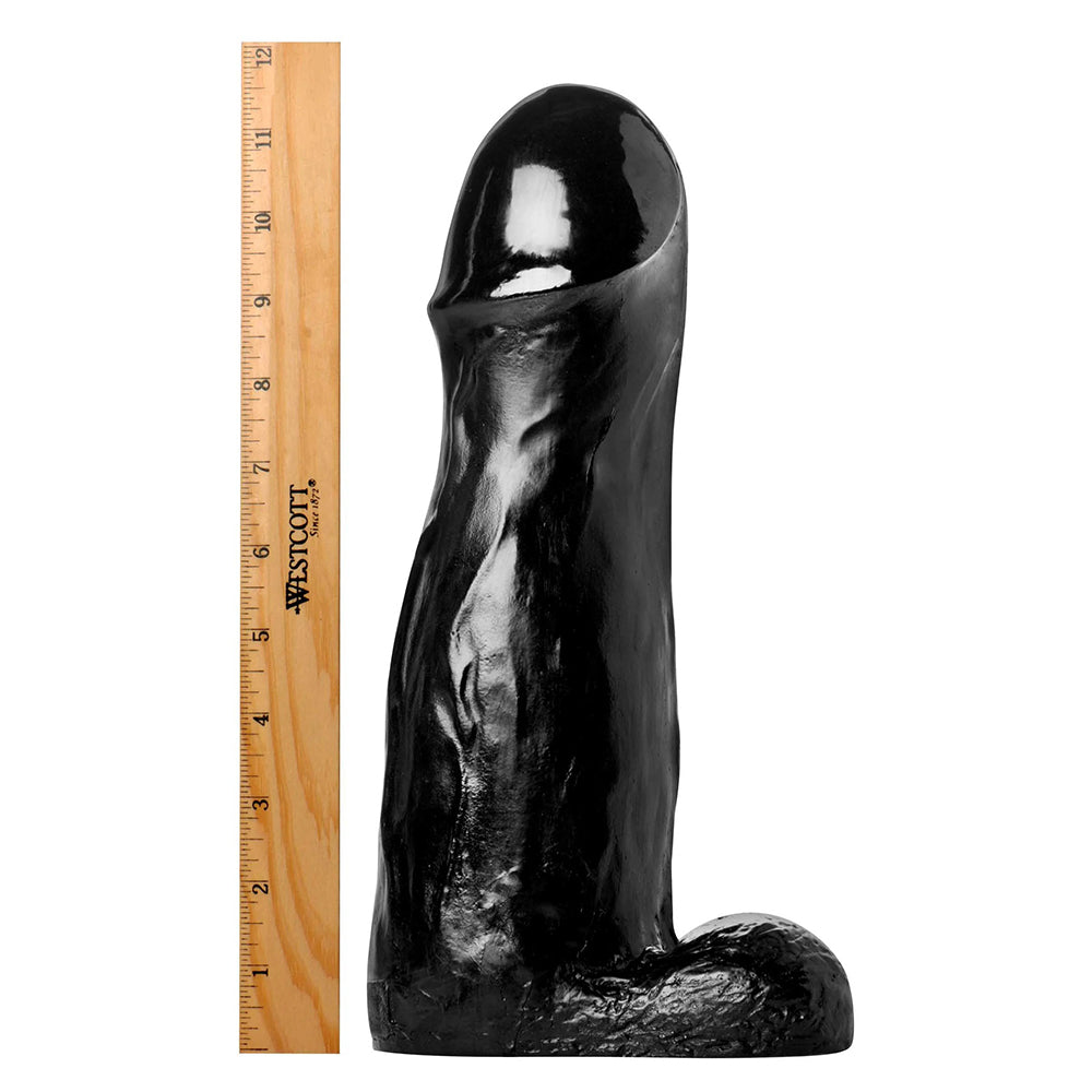 Black silicone dildo next to a ruler on a white background