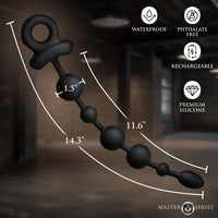 Black silicone beaded anal plug shown diagonally with measurement lines and text overlays indicating dimensions, alongside feature icons for waterproof, phthalate free, rechargeable, and premium silicone. Masterpiece branding is visible at the bottom right.