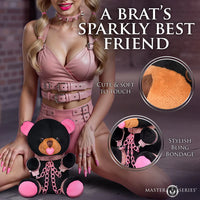 Person holding a plush toy with decorative chains, labeled 'A Brat's Sparkly Best Friend' by Master Series.
