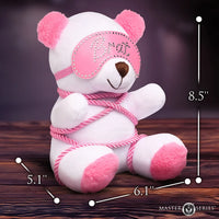 White teddy bear with pink accents and measurements on a wooden surface