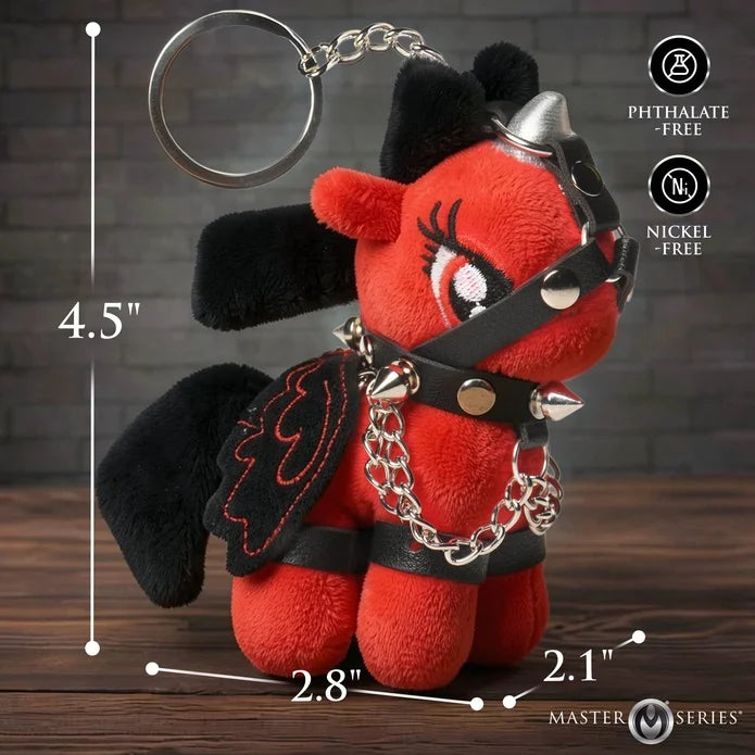 Red plush keychain with black accents and measurements on a wooden surface.