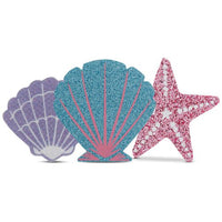 Three glittery sea-themed pasties shaped like a shell and starfish on a white background